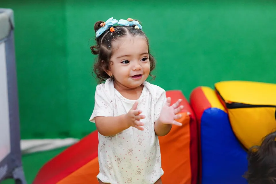 Bebê batendo palmas no espaço com almofadas coloridas